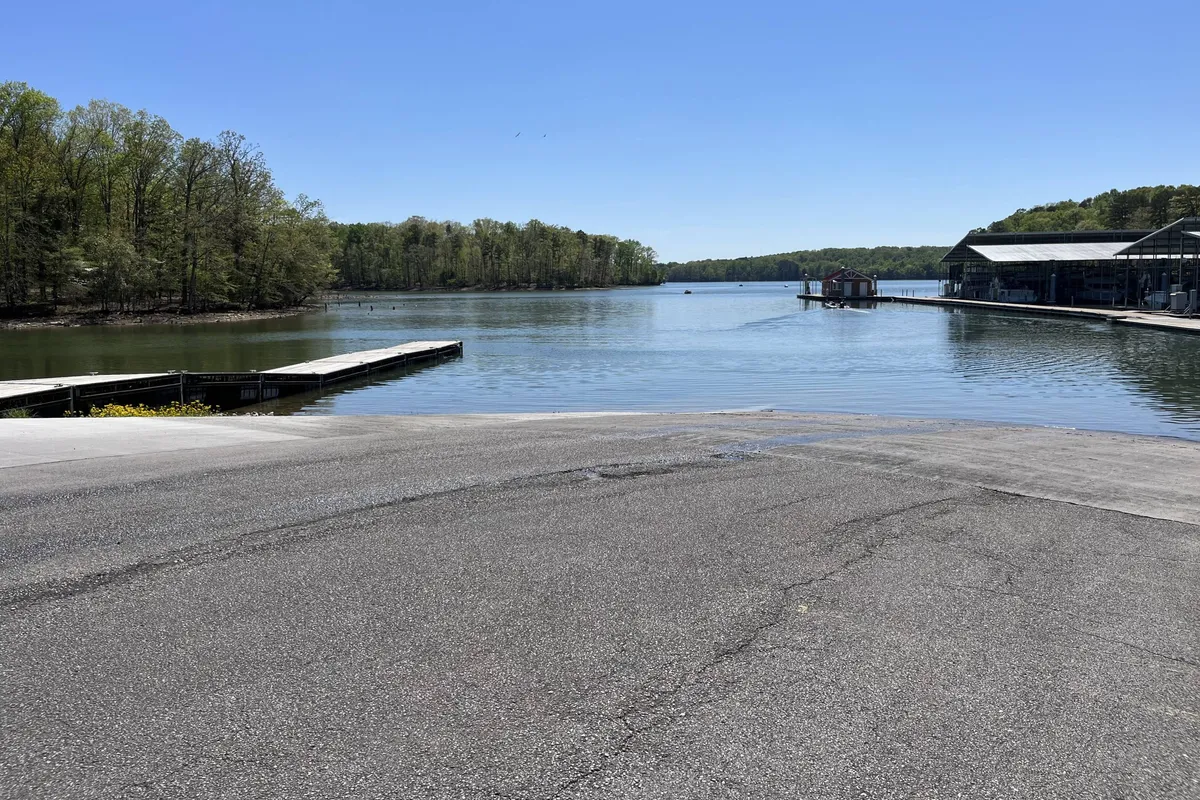 A tranquil lakeside setting with calm water, docks, and lush trees surrounding a few boathouses. The lighting suggests early evening, adding warmth and a sense of winding down after a day of adventure.