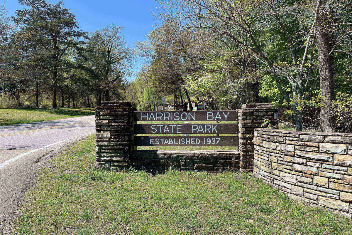 This image features the iconic entrance sign for Harrison Bay State Park set between stone pillars, surrounded by mature trees and lush greenery. The welcoming, well-maintained area suggests easy park access and sets the stage for outdoor adventures.