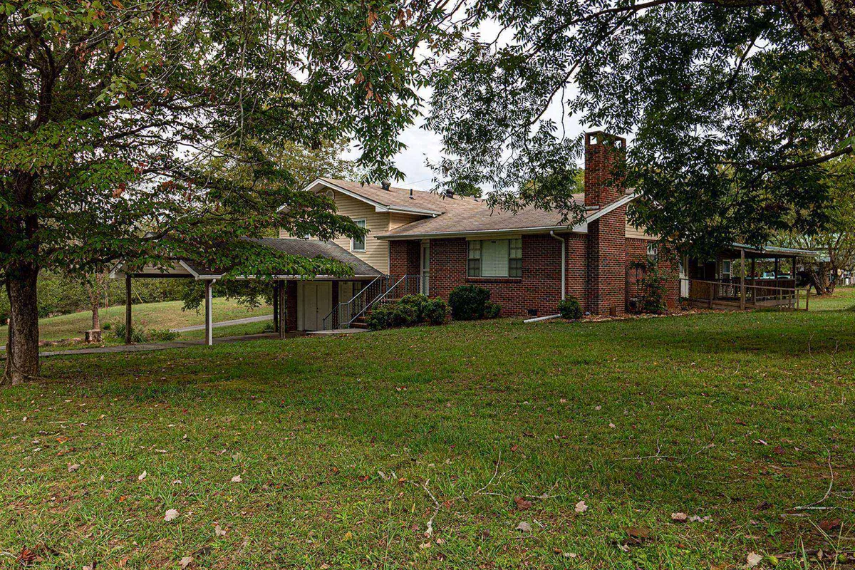 The home's brick exterior showcases a spacious covered porch overlooking a large, open yard. The scene suggests a seamless transition from indoor comfort to outdoor enjoyment, with ample room for gatherings and relaxation.