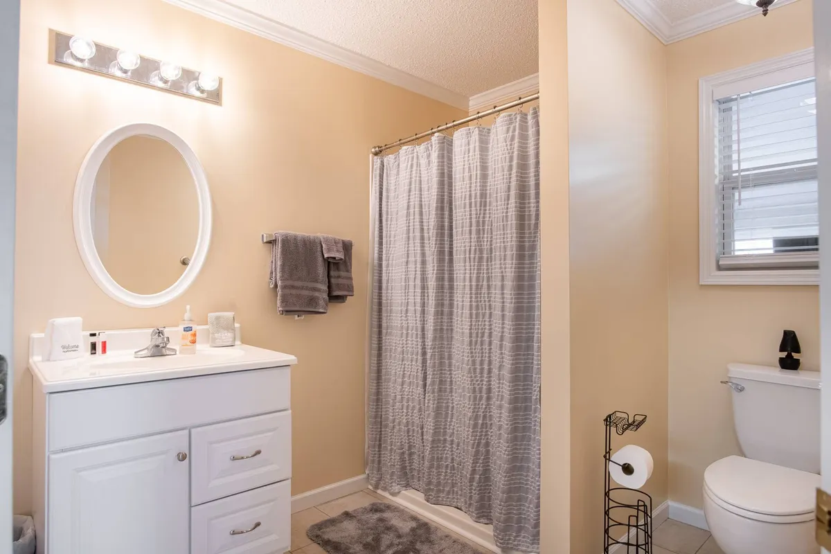 A well-organized bathroom with a modern vanity, mirror, shower area, and toilet. The clean, serene setup offers a restful spot for morning or evening routines.