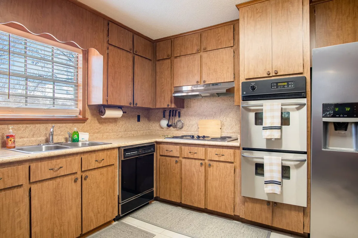 A cozy kitchen with wooden cabinetry, stainless steel appliances, a kitchen sink, and ample countertop space. The kitchen is warm and functional, ideal for preparing and enjoying meals. Small appliances and cookware are visible, reinforcing its fully equipped nature.